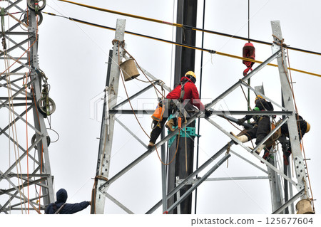 Dismantling an old electricity transmission tower - Scaffolders at work Dismantling an old electricity transmission tower - Scaffolders at work 125677604