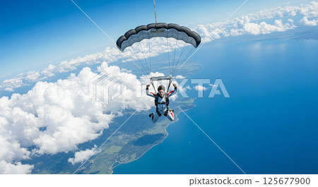 Skydivers flying through the sea of clouds and blue sky 125677900