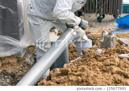 下水管道：建築工人將黏合劑（潤滑劑）塗抹到排水管上 125677993