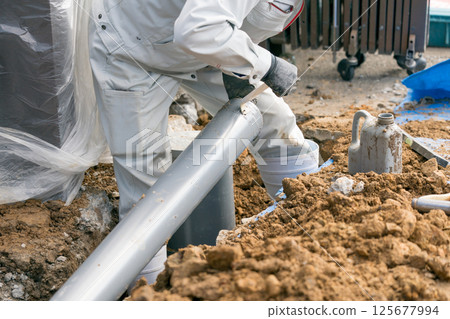 下水管道：建築工人將黏合劑（潤滑劑）塗抹到排水管上 125677994