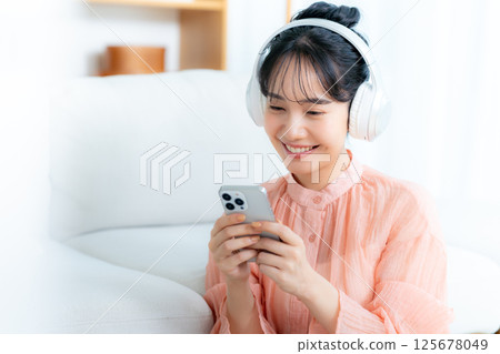 Young woman listening to music in the room Young woman listening to music in the room 125678049