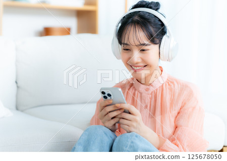Young woman listening to music in the room Young woman listening to music in the room 125678050