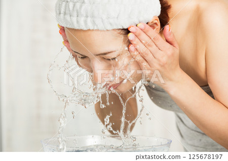 Young Asian woman is washing her face. Young Asian woman is washing her face. 125678197