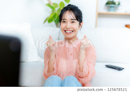 一位年輕的女士在客廳裡看電視 125678521