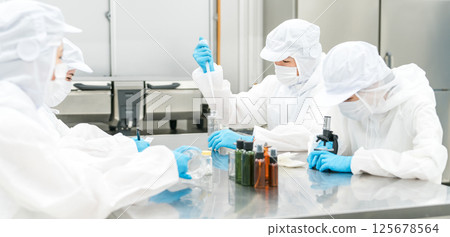 Staff wearing clean suits developing drugs at a pharmaceutical factory or pharmaceutical company 125678564