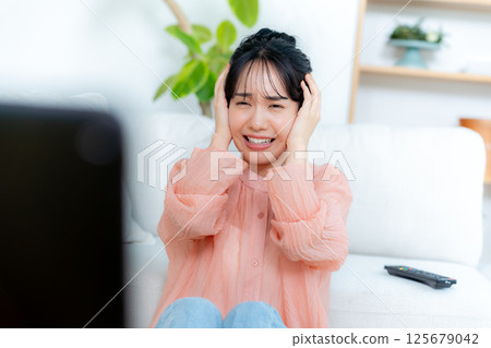 一位年輕的女士在客廳裡看電視 一位年輕的女士在客廳裡看電視 125679042