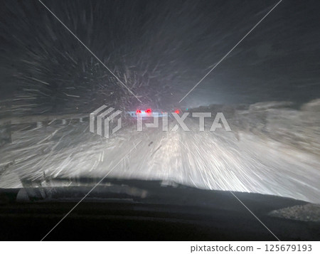 Driving on a snowy road at night 125679193