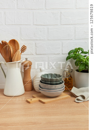 Kitchen utensils, bowls and spices resting on wooden countertop with white brick wall background Kitchen utensils, bowls and spices resting on wooden countertop with white brick wall background 125679819