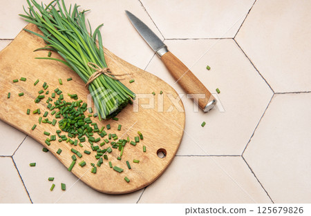 Freshly cut chives on wooden cutting board with knife 125679826