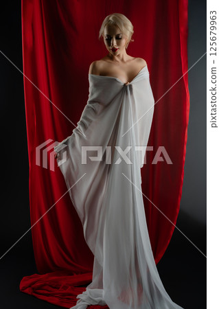 Elegant woman poses gracefully with flowing cloth in studio setting 125679963