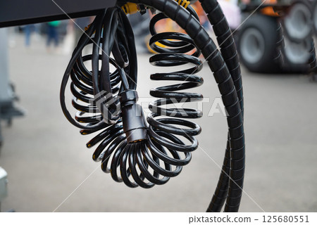 Close-up of coiled black cables in an outdoor setting. 125680551