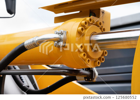 Hydraulic piston against the sky. a fragment of a yellow bulldozer 125680552