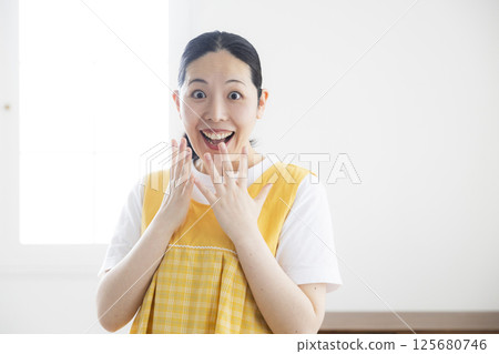 穿著黃色圍裙的中年婦女 穿著黃色圍裙的中年婦女 125680746