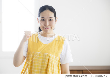 穿著黃色圍裙的中年婦女 穿著黃色圍裙的中年婦女 125680747