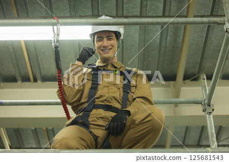 Male worker wearing a full harness 125681543