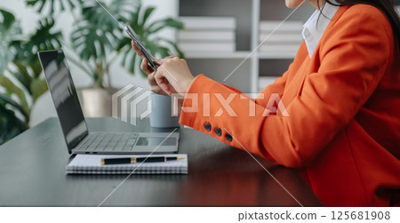 Businesswoman hand using laptop, tablet and smartphone in office. Digital marketing media mobile app and discussing plan new start up project. Finance task. 125681908