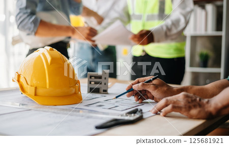 Three architects discussing new project. young men and women working together to form a new building. 125681921