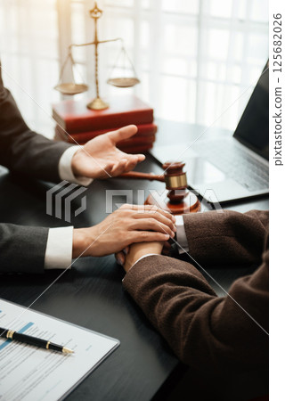 Judge gavel with scales of justice, Business and lawyer or counselor consulting and discussing contract papers with laptop and tablet at law firm 125682026
