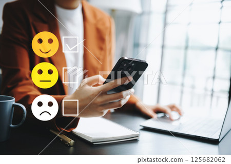 Customer service evaluation concept. woman Show face smile emoticon show on virtual screen from hand.looking at smart phone, tablet and laptop Customer service evaluation concept. woman Show face smile emoticon show on virtual screen from hand.looking at smart phone, tablet and laptop 125682062