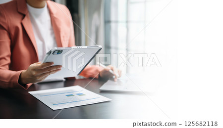 Businesswoman hand using laptop, tablet and smartphone in office. Digital marketing media mobile app and discussing plan new start up project. Finance task. 125682118