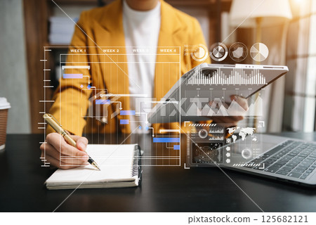 Businessman hand Project manager working and update tasks and Gantt chart scheduling virtual diagram.with smart phone, tablet and laptop Businessman hand Project manager working and update tasks and Gantt chart scheduling virtual diagram.with smart phone, tablet and laptop 125682121
