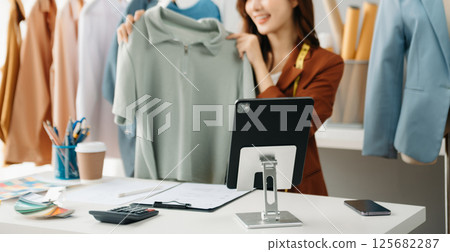 Fashion blogger concept, Young Asian women selling clothes on video streaming.Startup small business SME, using smartphone or tablet taking receive Fashion blogger concept, Young Asian women selling clothes on video streaming.Startup small business SME, using smartphone or tablet taking receive 125682287