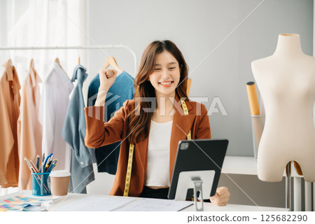 Diverse female fashion designers at work with tailor centimeters on necks and holds tablet and smartphone. independent creative design 125682290
