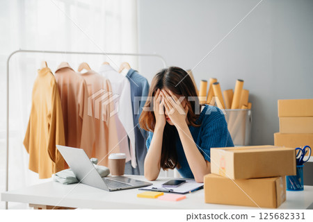 Young woman running online store Startup small business SME, using smartphone or tablet taking receive and checking online purchase shopping 125682331