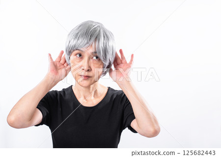 A gray-haired senior woman listening intently 125682443