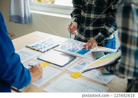 UX developer and ui designer brainstorming about mobile app interface wireframe design with customer breif and color code at modern office. UX developer and ui designer brainstorming about mobile app interface wireframe design with customer breif and color code at modern office. 125682618