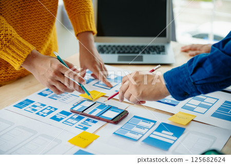 View of UI developer team brainstorming on their project with laptop, smartphone and digital tablet. Creative digital development agency. View of UI developer team brainstorming on their project with laptop, smartphone and digital tablet. Creative digital development agency. 125682624