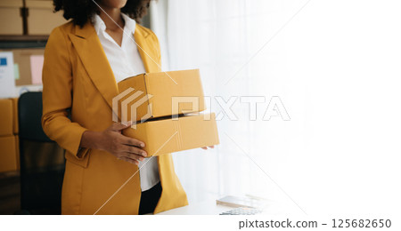 Young woman holding a smartphone, tablet showing payment success with yellow parcel box as online shopping concept 125682650