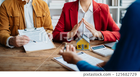 Female real estate agent is use hands to protect red roof for the concept of real estate investment about house trading, purchase at desk in office 125682729