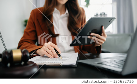 justice and law concept.Male judge in a courtroom  the gavel, working with smart phone and laptop and digital tablet computer on wood table in morning light 125682736
