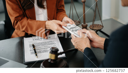 justice and law concept.passing bribe money in the envelop at lawyer office. businessman hand taking bribe money from female 125682737