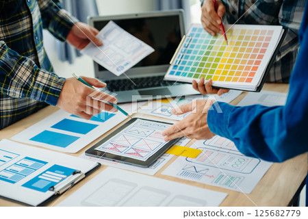 UX developer and ui designer brainstorming about mobile app interface wireframe design with customer breif and color code at modern office. UX developer and ui designer brainstorming about mobile app interface wireframe design with customer breif and color code at modern office. 125682779