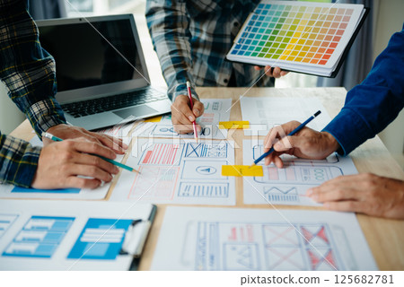 View of UI developer team brainstorming on their project with laptop, smartphone and digital tablet. Creative digital development agency. View of UI developer team brainstorming on their project with laptop, smartphone and digital tablet. Creative digital development agency. 125682781