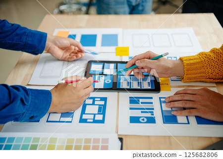 View of UI developer team brainstorming on their project with laptop, smartphone and digital tablet. Creative digital development agency. View of UI developer team brainstorming on their project with laptop, smartphone and digital tablet. Creative digital development agency. 125682806