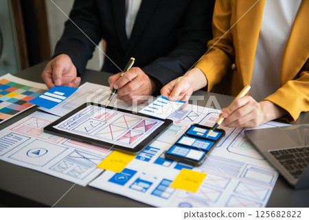 UX developer and ui designer brainstorming about mobile app interface wireframe design with customer breif and color code at office. UX developer and ui designer brainstorming about mobile app interface wireframe design with customer breif and color code at office. 125682822