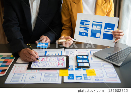 UX developer and ui designer brainstorming about mobile app interface wireframe design with customer breif and color code at office. UX developer and ui designer brainstorming about mobile app interface wireframe design with customer breif and color code at office. 125682823