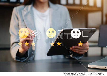 Customer service evaluation concept. Businesswoman pressing face smile emoticon show on virtual screen at tablet and smartphone 125682897