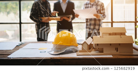Engineer desk with object paper and tablet with blurry engineer teamwork hardworking to consults about their building project. 125682919