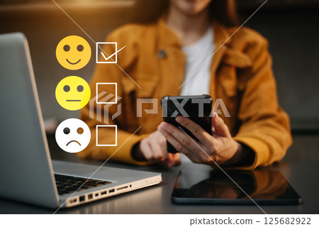 Customer service evaluation concept. woman Show face smile emoticon show on virtual screen from hand.looking at smart phone, tablet and laptop 125682922