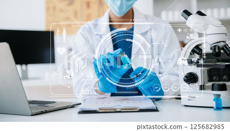 Young scientists conducting research investigations in a medical laboratory, a researcher in the foreground is using a microscope in laboratory for medicine. 125682985