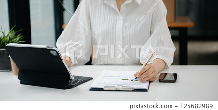 Woman hand using laptop, tablet and smartphone in office. Digital marketing media mobile app and discussing plan new start up project. Finance task. 125682989