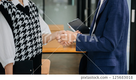 Two confident business man shaking hands during a meeting in the office, success, dealing, greeting and partner in sun light 125683018