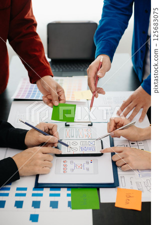 UX developer and ui designer brainstorming about mobile app interface wireframe design with customer breif and color code at modern office. UX developer and ui designer brainstorming about mobile app interface wireframe design with customer breif and color code at modern office. 125683075