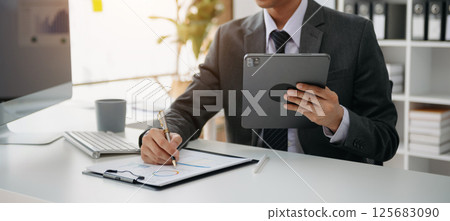 business documents on office desk with laptop and smart phone and graph business diagram and man working in office 125683090