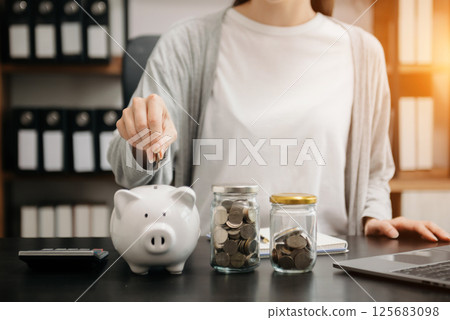 Woman hand holding coin with pig piggy bank. Saving and financial accounts concept Woman hand holding coin with pig piggy bank. Saving and financial accounts concept 125683098