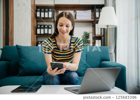 Caucasian businesswoman working in the office with working notepad, tablet and laptop documents on sofa in home office Caucasian businesswoman working in the office with working notepad, tablet and laptop documents on sofa in home office 125683396